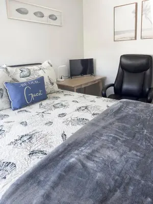 a bedroom with a bed with a blue pillow and a chair at Quaint Mid-Century Cottage by the Coast in Ventura