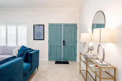 a living room with a blue couch and a mirror at Elegant Retreat w/ Game room in Heart of OC in Midway City