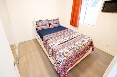 a bedroom with a bed with a comforter and a window at cozy small 2 bedroom in Koreatown/Hollywood in Los Angeles