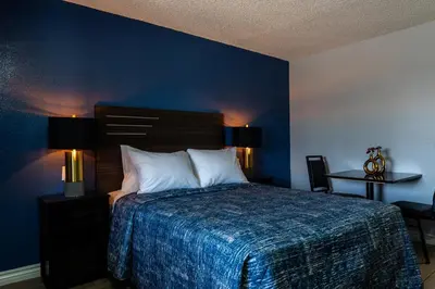 a bedroom with a bed with a blue wall at Pala Motel in Pomona