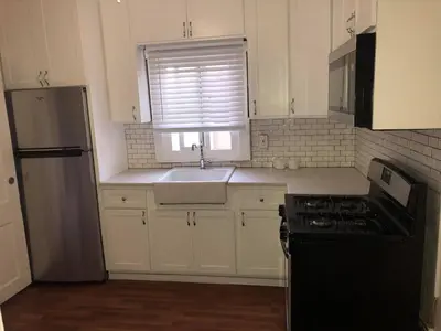 a kitchen with white cabinets and a sink and a window at DTLA Oasis Private Bedroom with Exclusive Laundry - Steps to the Heartbeat of LA in Los Angeles