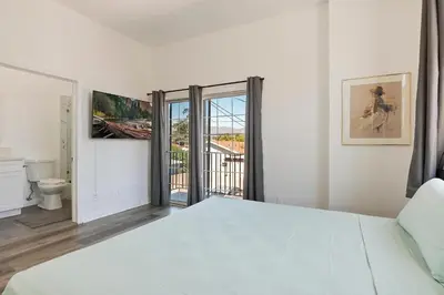 a white bedroom with a bed and a balcony at Spacious Private gated modern loft close to Universal Studio and Hollywood in Los Angeles