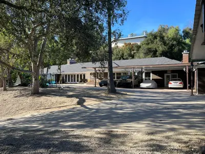 a house with cars parked in front of a driveway at Private Room View Gated 2Acre Estate - Female Share Indoor - Men Share Outdoor - SD in Encino