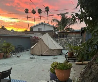 a tent in a courtyard with a sunset in the background at Serene Studio, Yurt Barn near DTLA Silverlake in Glendale