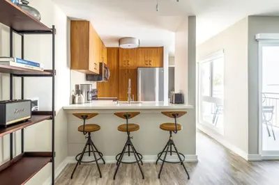a kitchen with wooden cabinets and bar stools at Redondo Beach 1BR w Pool Gym nr Beach LAX-398 in Redondo Beach