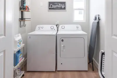 a laundry room with two white washers and a counter at Charming Disneyland Retreat - Sleeps up to 12 w Game Room, Pool Table, EV w King Bed in Midway City