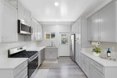 a white kitchen with white cabinets and a stove at Stylist Home In Convenient Location! in Temple City