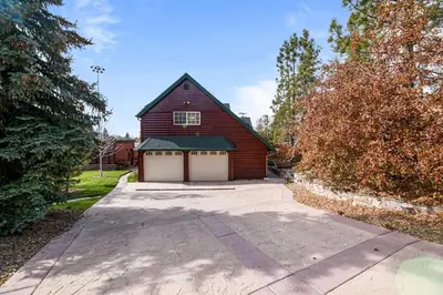 a red barn with two garage doors on a driveway at Serene Lakefront Haven by Rather Be Properties in Big Bear Lake