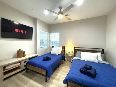 a bedroom with two beds and a tv on the wall at Amazing Value with High Comfort, 14 Guests for 4BR by Disneyland, Beaches, Rodeo 39 & More in Midway City