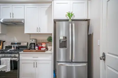 a stainless steel refrigerator in a kitchen with white cabinets at Amazing Value with High Comfort, 14 Guests for 4BR by Disneyland, Beaches, Rodeo 39 & More in Midway City