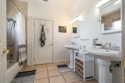 a white bathroom with two sinks and a shower at Hills of Studio City, your serene home away from Home in Studio City