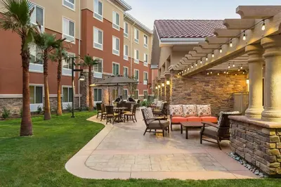 a patio with chairs and tables and a building at Homewood Suites by Hilton San Bernardino in San Bernardino