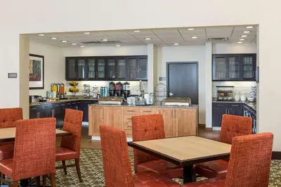 a restaurant with tables and chairs and a kitchen at Homewood Suites by Hilton San Bernardino in San Bernardino