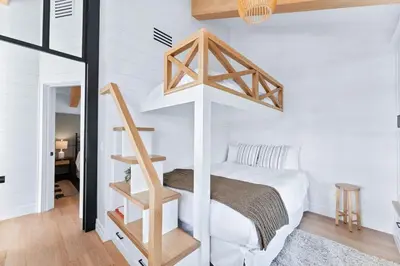 a bedroom with a white bed and a wooden staircase at Majestic Lakeview Lodge in Lake Arrowhead