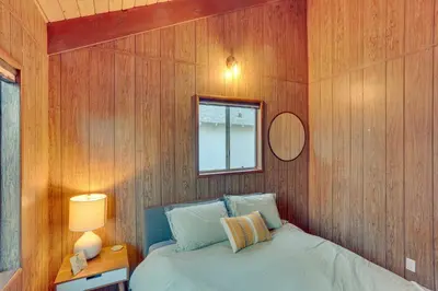 a bedroom with wooden walls and a bed with a window at Crestline Cabin Mountain Views and Fire Pit! in Crestline