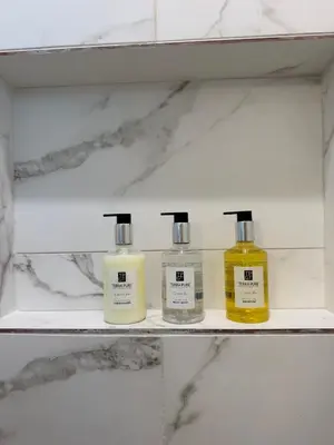 three bottles of moisturizers sit on a shelf in a bathroom at Coastal Escape in Redondo Beach in Redondo Beach