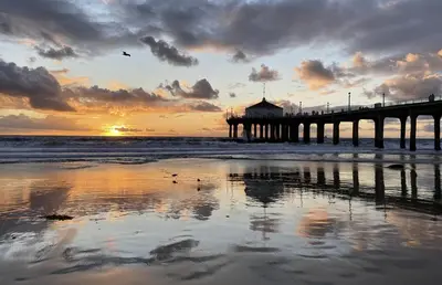 a pier on the beach with a sunset in the background at Coastal Escape in Redondo Beach in Redondo Beach