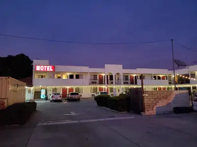 a hotel with cars parked in a parking lot at night at Eunice Plaza Motel in El Monte