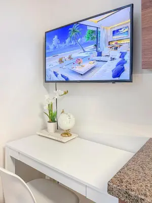 a tv hanging on a wall above a white desk at MDR Studio Apartment Luxury pool, gym, parking, jacuzzi. in Los Angeles