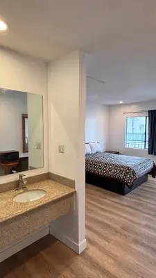 a bathroom with a bed and a sink and a mirror at Budget inn Whittier in Whittier