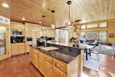 a kitchen with wooden cabinets and a living room at Gold Rush Lodge Big Bear~Hot Tub~ Games~ in Big Bear Lake