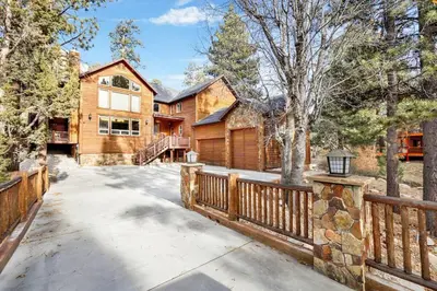 a home with a wooden fence and a driveway at Gold Rush Lodge Big Bear~Hot Tub~ Games~ in Big Bear Lake