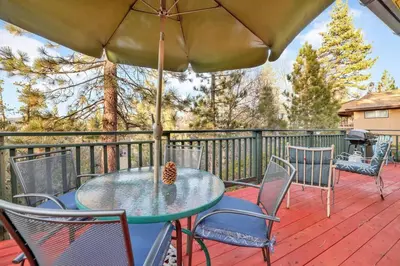 a table and chairs on a deck with an umbrella at A Hidden Asset Big Bear~ Hot Tub~ Walk to Village~ in Big Bear Lake