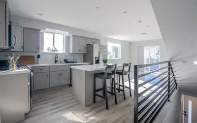 a kitchen with white cabinets and a island with bar stools at Normandie Hostel in Los Angeles