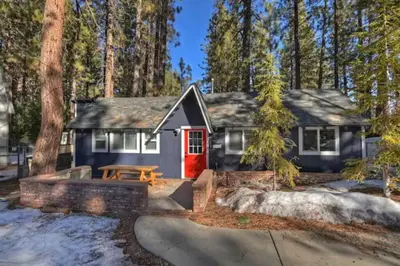 a house with a red door in the woods at Modern Moab: Near Boulder Bay + Spa + Large Yard in Big Bear Lake
