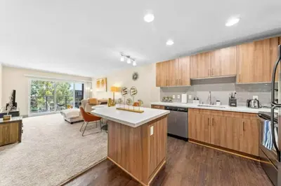 a kitchen with wooden cabinets and a living room at The Moonstone - Cozy Marina side Garden View Pool and Gym in Los Angeles