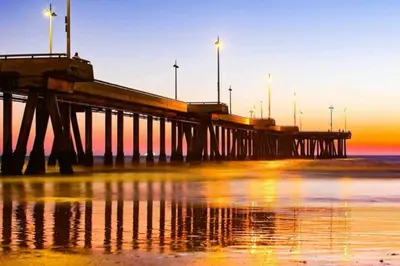 a pier with lights on the beach at sunset at The Moonstone - Cozy Marina side Garden View Pool and Gym in Los Angeles