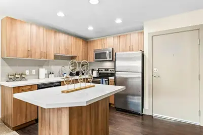 a kitchen with wooden cabinets and a stainless steel refrigerator at The Moonstone - Cozy Marina side Garden View Pool and Gym in Los Angeles
