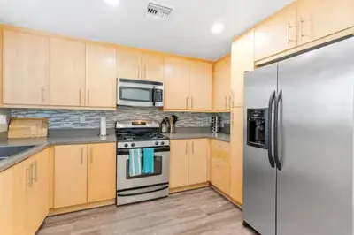a kitchen with wooden cabinets and a stainless steel refrigerator at Harbor Views Retreat By Venice Beach In Marina DR in Los Angeles