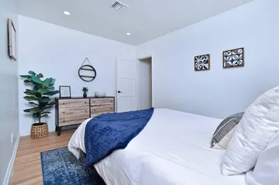 a white bedroom with a large bed and a dresser at Beautiful 3 Bed Home with a Large Back Yard Outdoor Space in Los Angeles