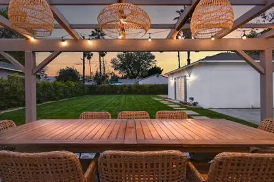 a wooden table and chairs under a pergola with lights at Beautiful 3 Bed Home with a Large Back Yard Outdoor Space in Los Angeles