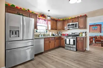 a kitchen with stainless steel appliances and wooden cabinets at The Disneyland Dream by OC Adventure Homes in Garden Grove