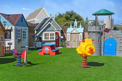 a toy park with play equipment in the grass at The Disneyland Dream by OC Adventure Homes in Garden Grove