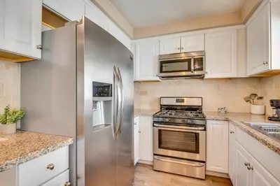a kitchen with white cabinets and a stainless steel refrigerator at LA Condo about 1 Mi to The Kia Forum and SoFi Stadium in Inglewood