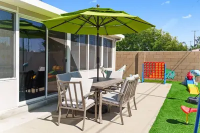 a wooden table and chairs with a green umbrella at Gamers Getaway by OC Adventure Homes in Stanton