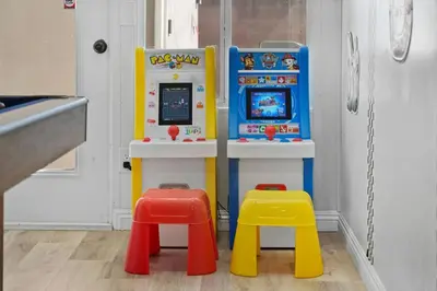 a toy video game machine with two stools at Gamers Getaway by OC Adventure Homes in Stanton