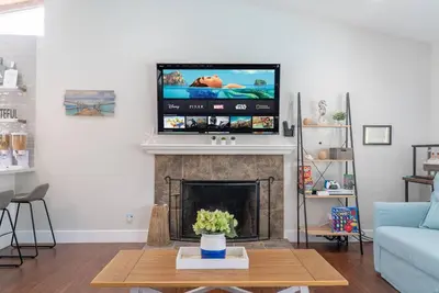 a living room with a tv above a fireplace at Underwater Voyage by OC Adventure Homes in Garden Grove