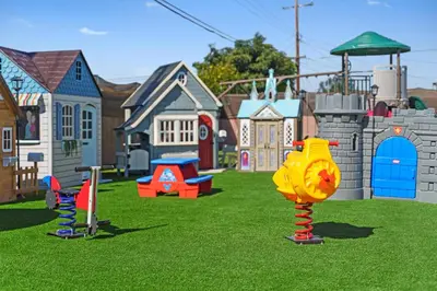 a toy park with play equipment in the grass at The Disneyland Dream by OC Adventure Homes in Garden Grove
