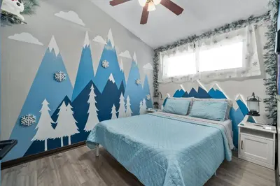 a bedroom with a blue bed with snowy trees on the wall at Great Outdoors by OC Adventure Homes in Garden Grove