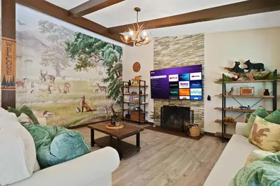 a living room with a fireplace and a large screen tv at Great Outdoors by OC Adventure Homes in Garden Grove