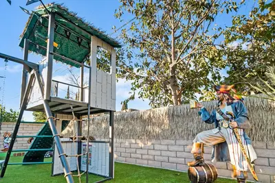 a statue of a man sitting on a wall next to a tower at Pirate Cove by OC Adventure Homes in Garden Grove
