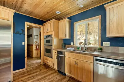 a kitchen with wooden cabinets and a blue wall at Slope Vista Escape in Fawnskin
