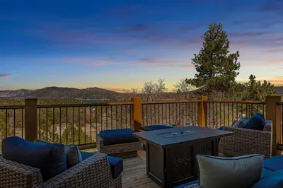 a patio with chairs and a table on a deck at Sky High Mountain Lodge Lake View in Big Bear Lake