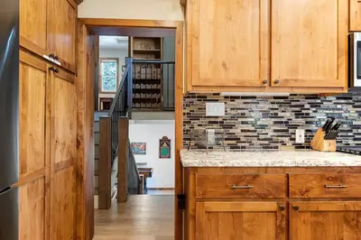 a kitchen with wooden cabinets and a staircase at Snowcrest Lodge in Exclusive Fox Farm in Big Bear Lake
