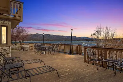 a deck with tables and chairs with a view of the water at HoneyBear Lodge Lakefront in Big Bear Lake