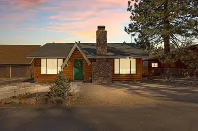 a wooden house with a chimney and a green door at Honeybee by the Bay in Big Bear Lake in Big Bear Lake